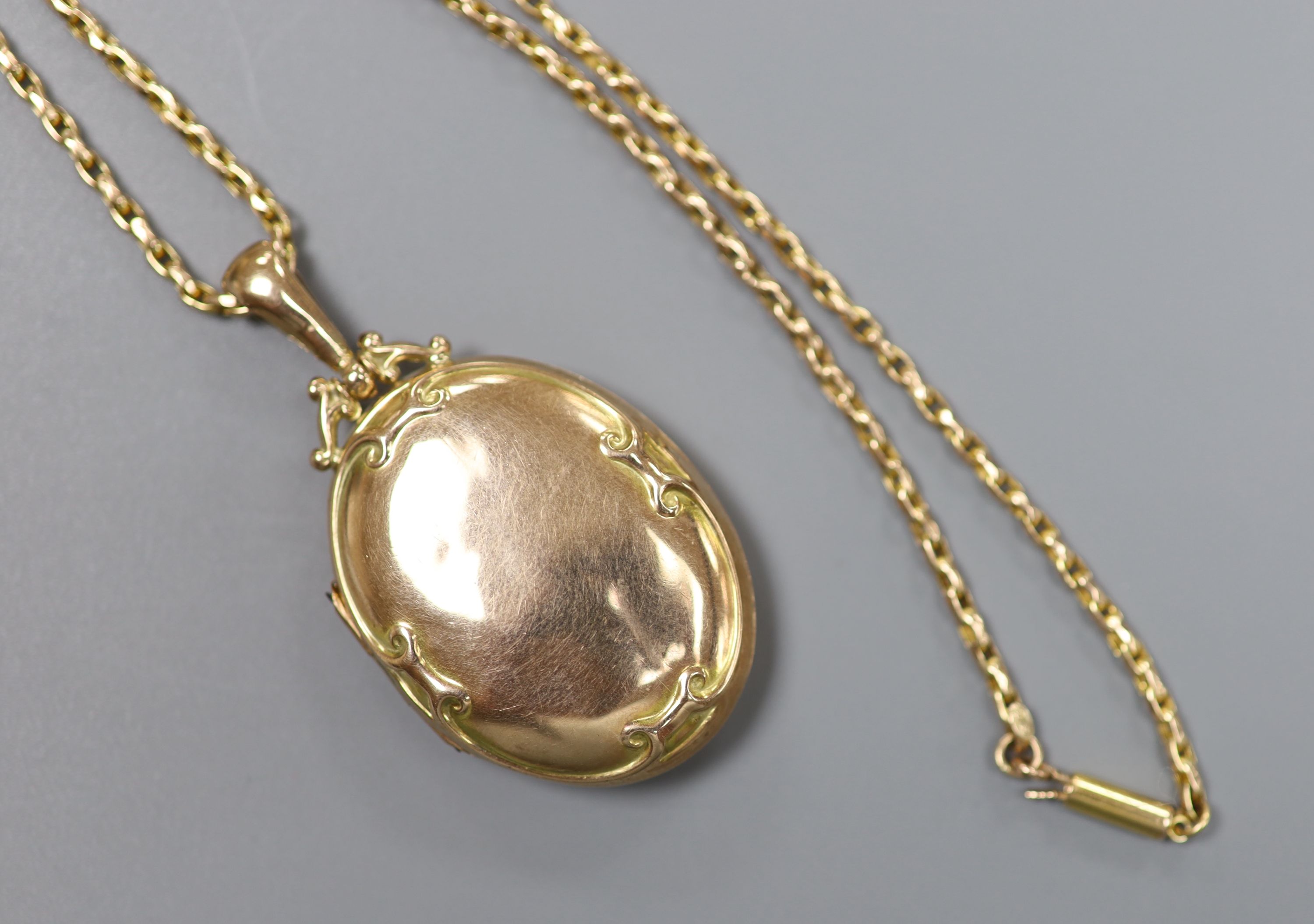 An Edwardian Art Nouveau 9ct gold oval locket, on a 9ct chain